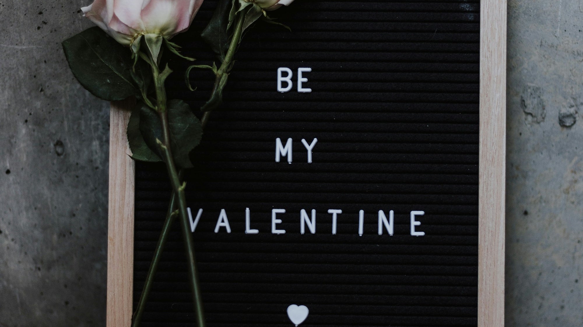 Rose laying on board that says "Be My Valentine".