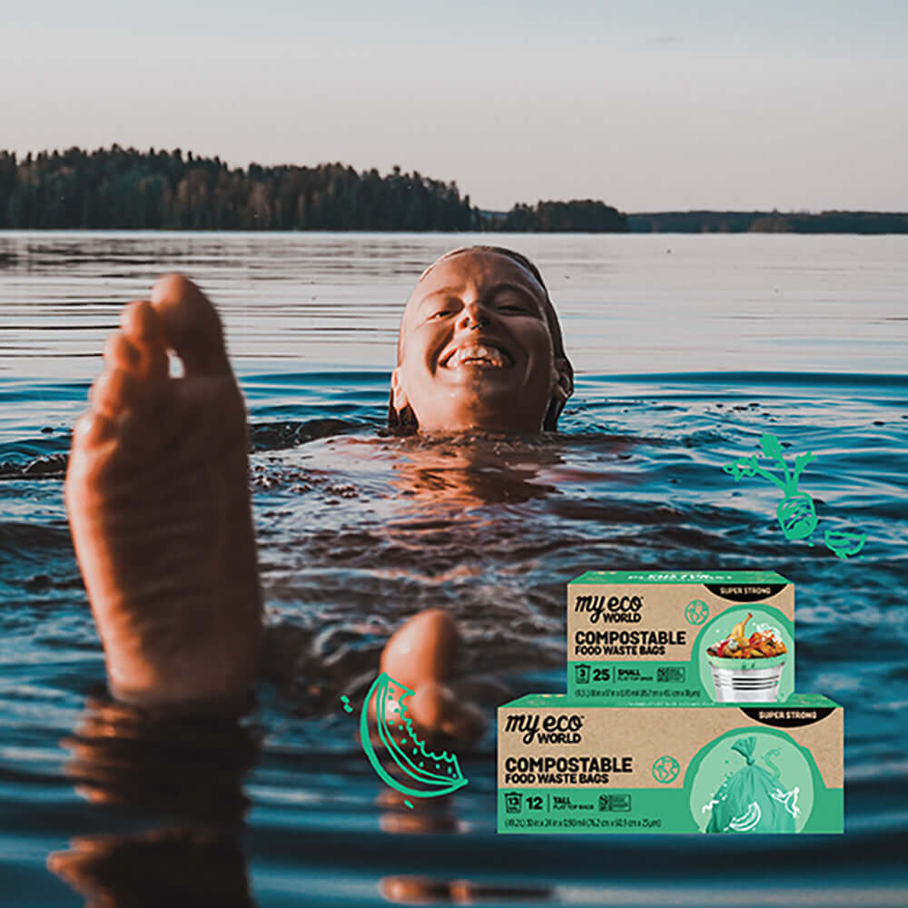 A person floating joyfully in a serene lake, capturing the essence of connection with nature. In the foreground, two packages of MyEcoWorld® compostable food waste bags are prominently displayed. The packaging emphasizes eco-friendly disposal solutions, showing that small lifestyle changes like using compostable waste bags can contribute to preserving nature's beauty.