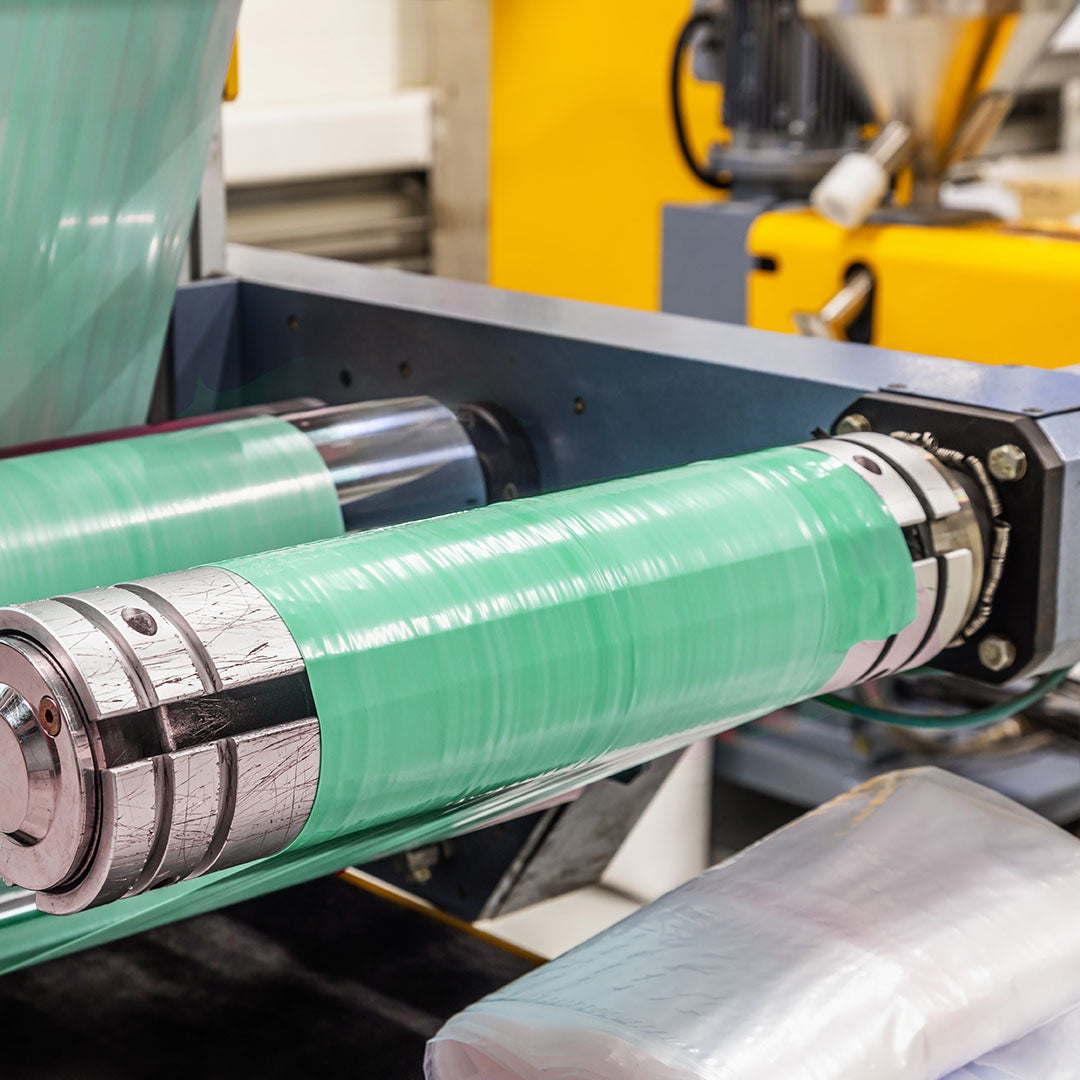 Machine in operation producing biodegradable garbage bags and compostable bin bags, showcasing the manufacturing process of eco-friendly waste management products. The image highlights the production of sustainable materials like PBAT for degradable garbage bags.