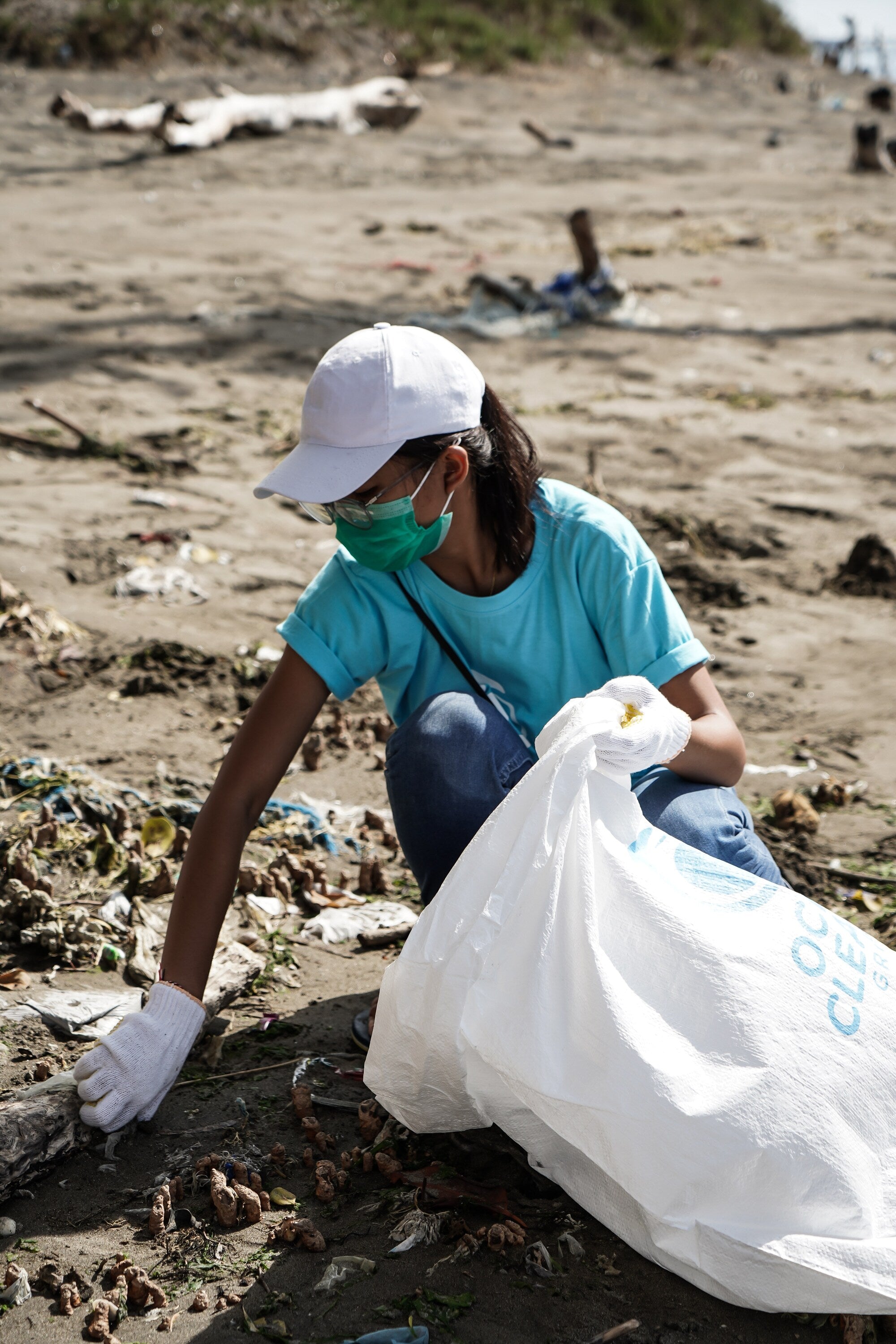 Person cleaning up trash on beach. 